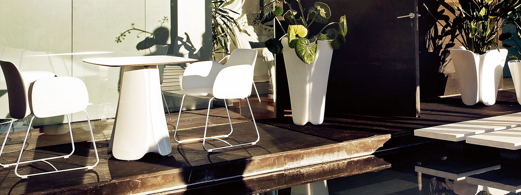 Image of Vondom Pezzettina modern garden table and chairs on sunny decking next to water feature