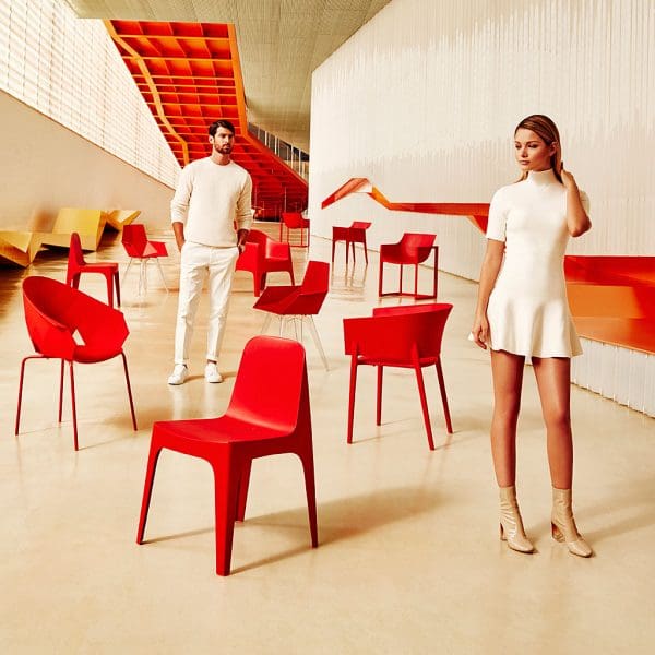 Image of man and woman dressed in white stood in between different red coloured Vondom chairs