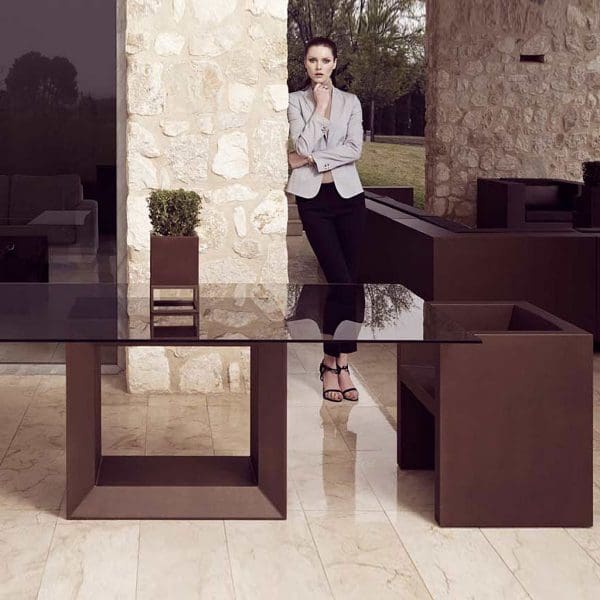 Image of Vondom Vela brown garden dining furniture on terrace with lady in the background leaning against a wall