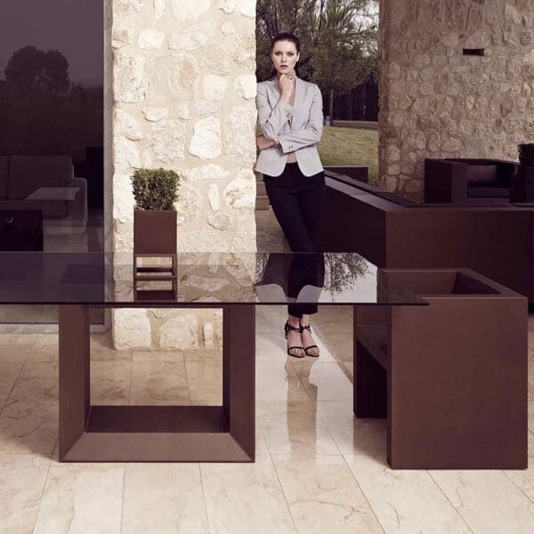 Image of Vondom Vela brown garden dining furniture on terrace with lady in the background leaning against a wall