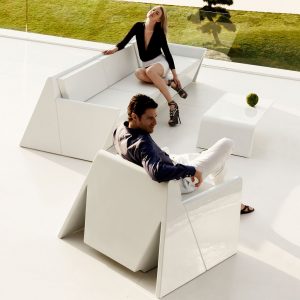 Image of couple sat relaxing in white Rest outdoor lounge chair and sofa by Vondom on terrace at dusk