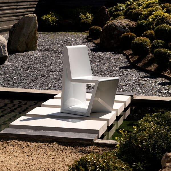 Image of Rest white garden dining chair by Vondom on stepping stone surrounded by water