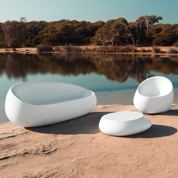Image of Stone white plastic garden sofa, lounge chair and low table by Vondom on arid, sunny shore of lake