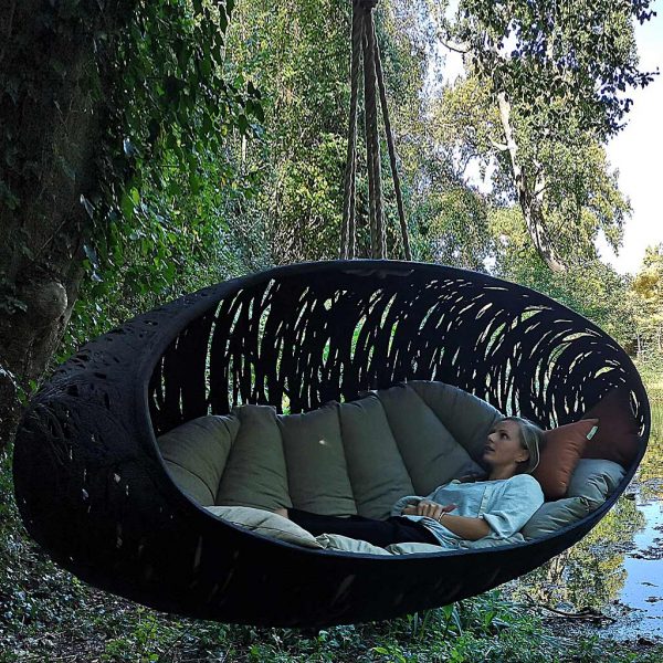 Image of woman lying inside Bios Alpha sofa swing seat by Unknown Nordic, with pond in background