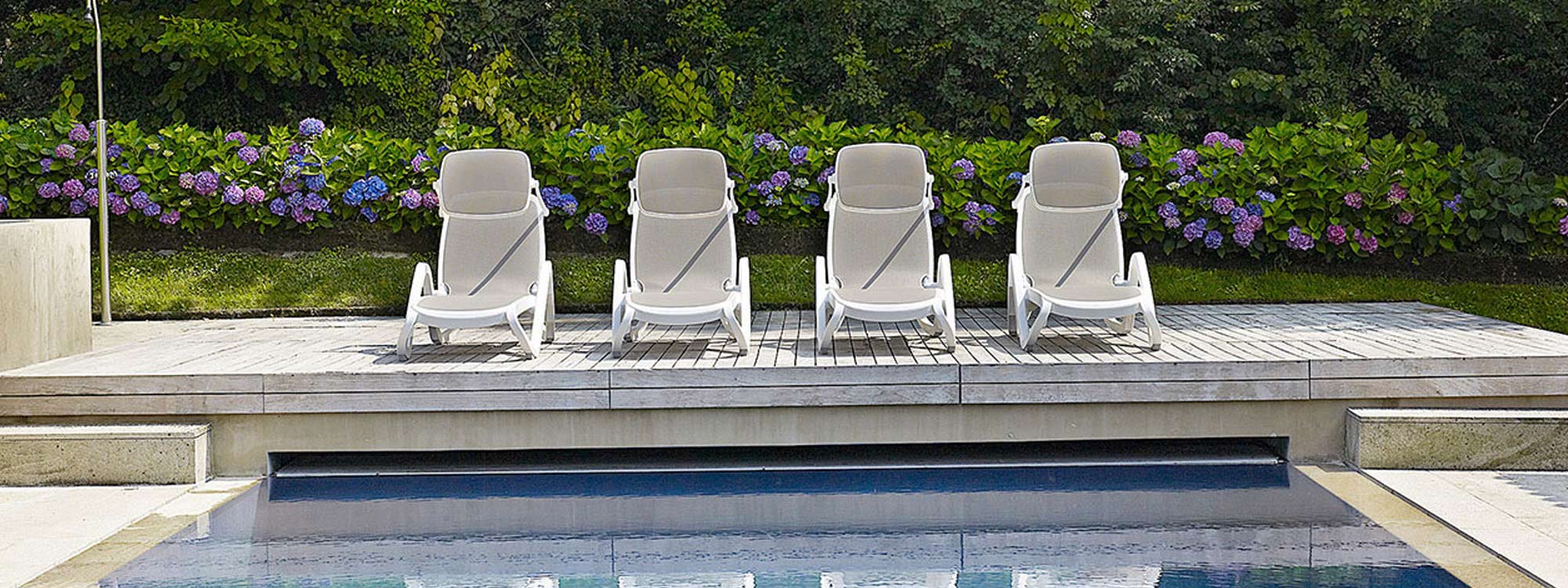 Image of row of Alfa white PP stacking sun loungers by Nardi along a poolside