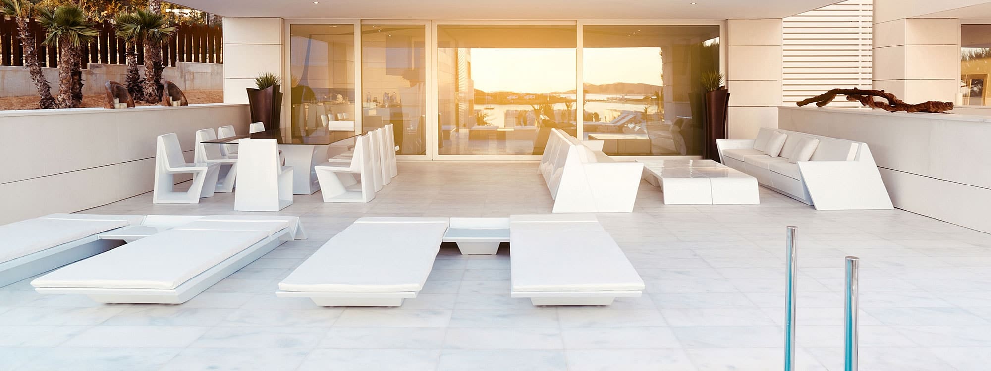 Image of modern terrace in late afternoon sun, with Rest garden dining furniture, outdoor sofas and white dining set by Vondom