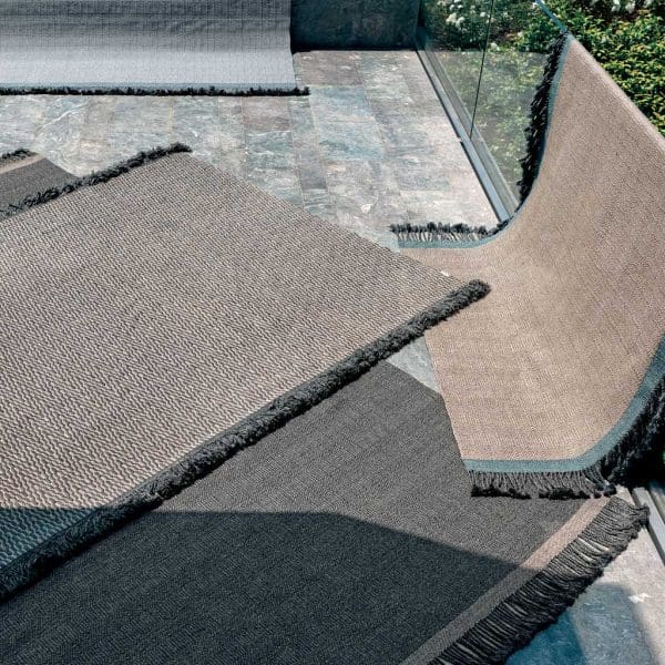 Image of different RODA Atlas garden rugs laid out on terrace in sun