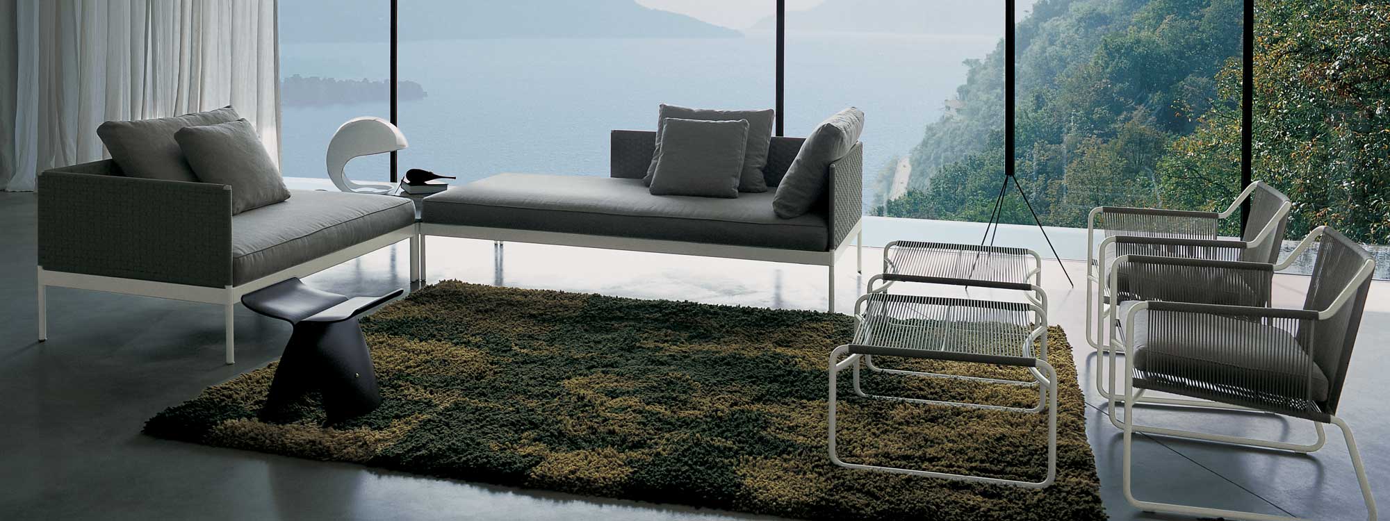 Image of RODA Basket minimalist garden sofa and Harp outdoor lounge chairs in living room overlooking expanse of Italian lake and steep hillsides