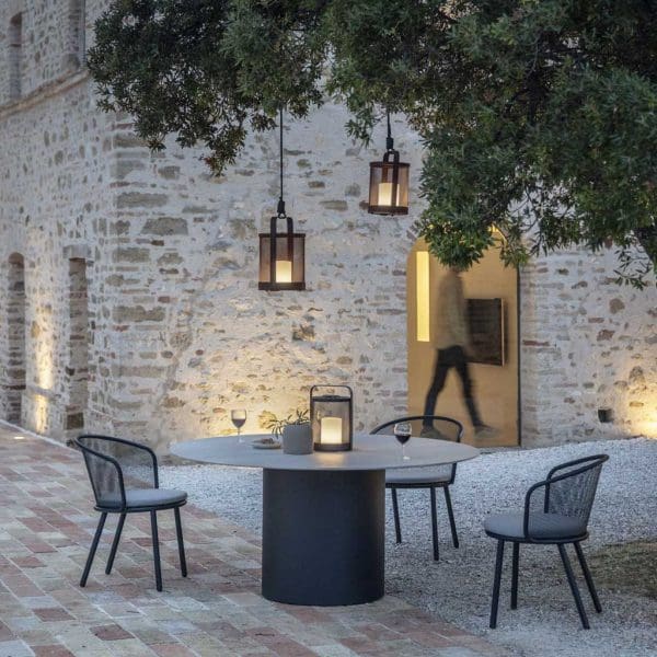 Image of courtyard at dusk with Baza contemporary outdoor chairs and Branta large round dining table