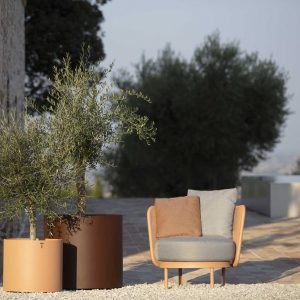 Image of Todus Baza lounge chair and Verdi minimalist plant pots in sun and shade of terrace, with trees and shrubs in background
