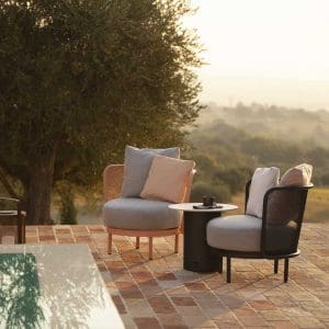 Dusk shot of Baza Club lounge chairs and Branta outdoor side table next to swimming pool