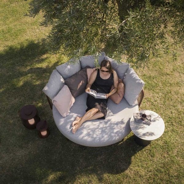 Image of aerial view of woman lying in Baza modern garden daybed on a grass lawn, in the shade of a tree