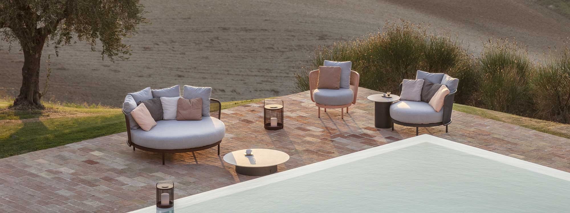 Image of Todus Baza modern garden lounge furniture on poolside together with Branta low tables, with warm light of early evening
