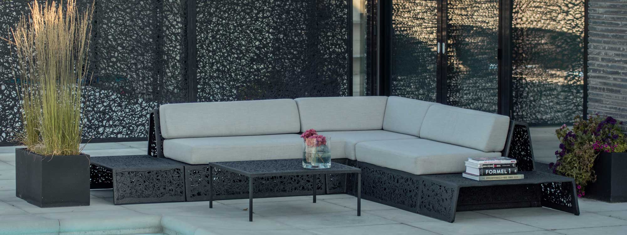 Image of black Bios Lounge furniture with grey cushions, with black lava fence panels in background by Unknown Nordic