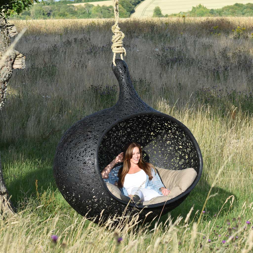 Image of Aimee enjoying the comfort of Bios Hide sofa swing beneath and oak tree in the West Sussex countryside