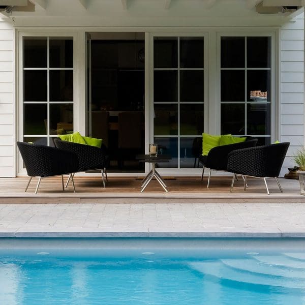 Image of black Shell modern garden lounge chairs on covered terrace with azure swimming pool in the foreground