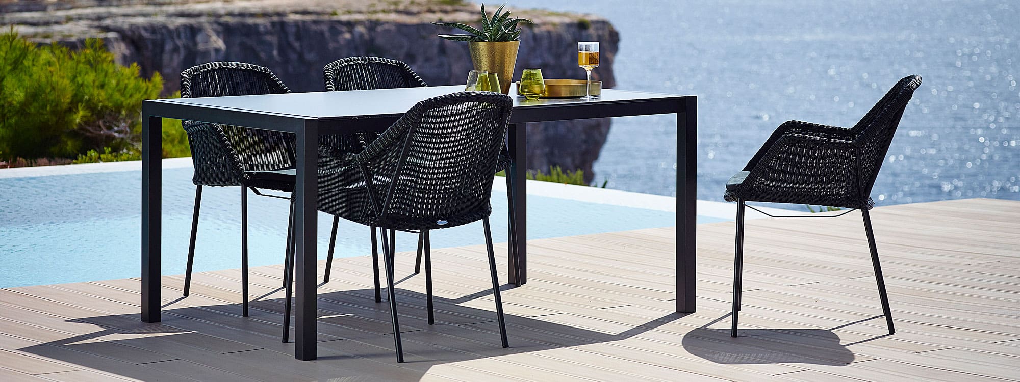 Image of black Cane-line Breeze chairs around a black dining table on cliff-top terrace