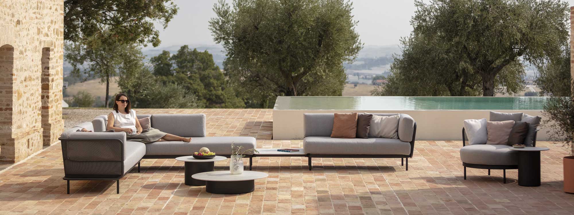 Image of large Baza garden sofa on sunny terrace with Branta low tables in the centre