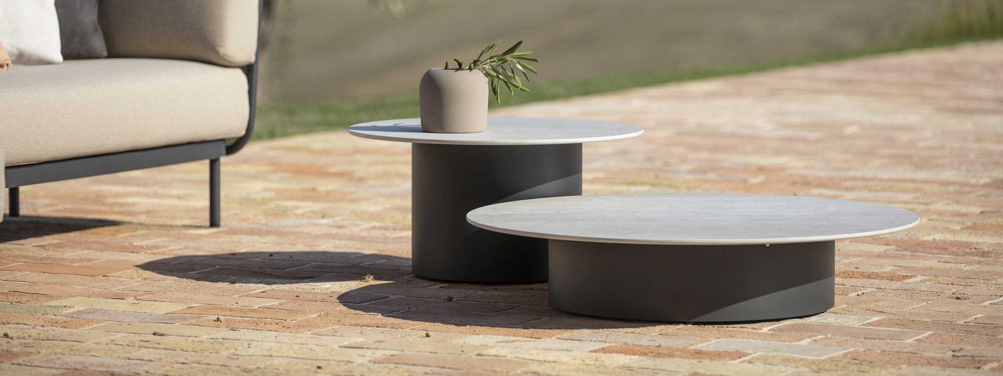 Image of pair of different heights of Todus Branta outdoor low tables next to Baza garden sofa on sunny terrace
