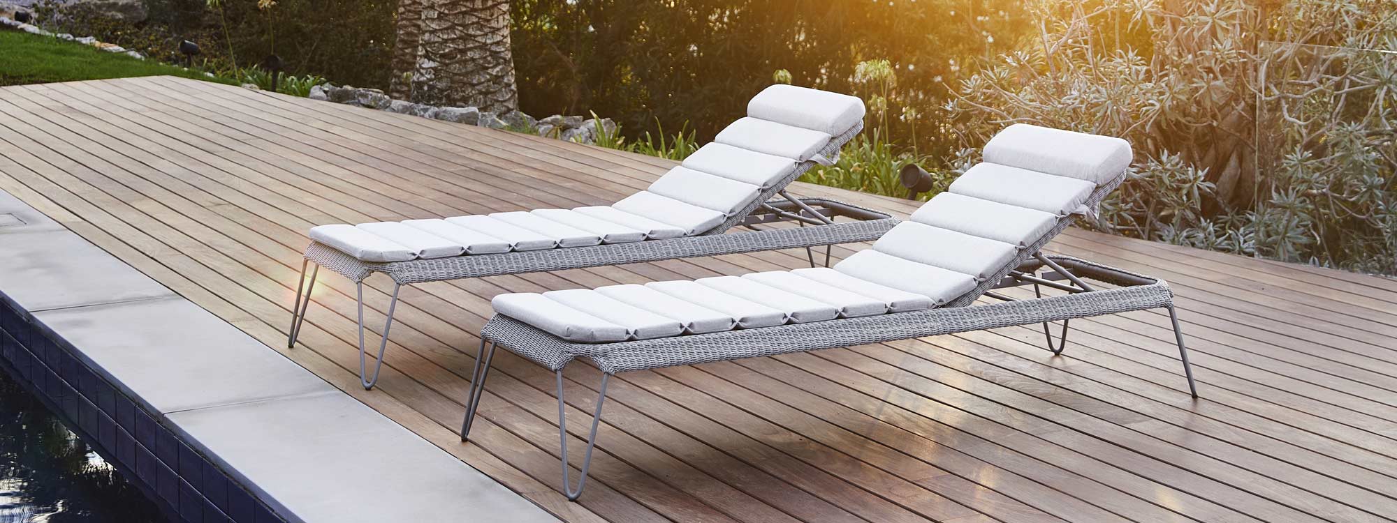 Image of pair of Cane-line Breeze grey sun loungers at dusk on decked poolside