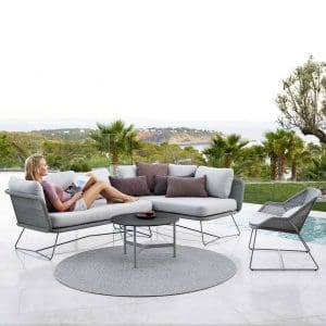 Image of woman reclining in light-grey Horizon rattan corner sofa with Twist light grey low tables by Caneline in the centre