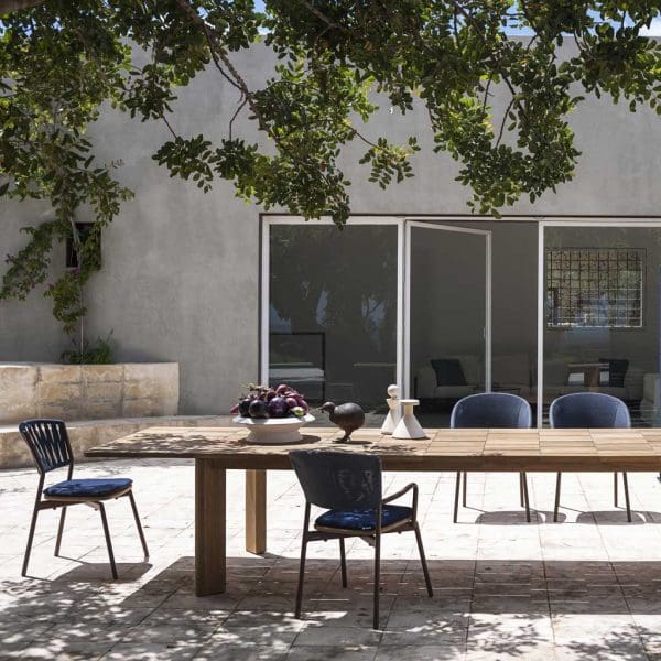 Image of RODA Brick extending teak table and Piper garden dining chairs beneath tree on sunny modern terrace