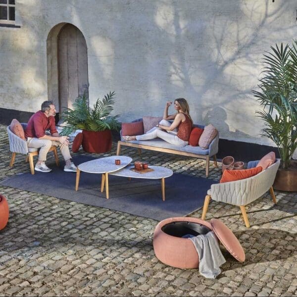 Image of couple relaxing on Royal Botania Calypso garden sofas in cobbled courtyard.