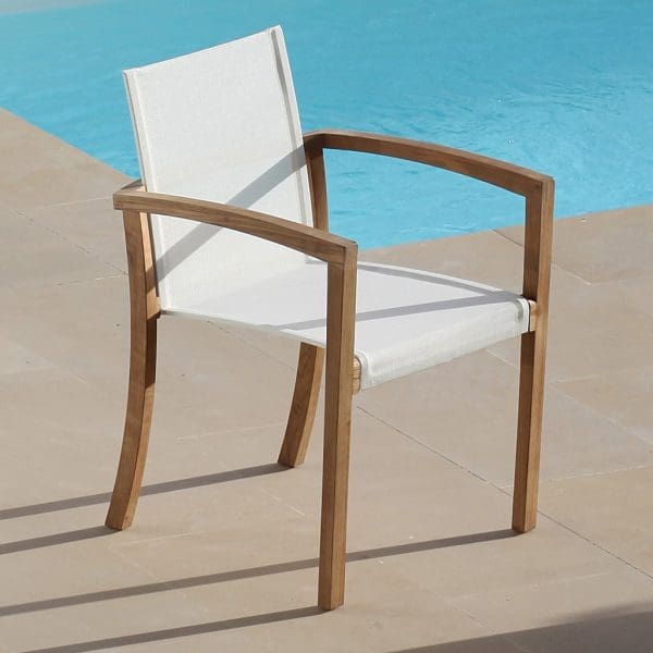 Image of XQI teak carver chair with white seat & back by Royal Botania, next to swimming pool.