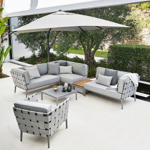 Image of light Grey Conic modern garden sofa and lounge chair in light grey by Cane-line, with olive tree and dry stone wall in background