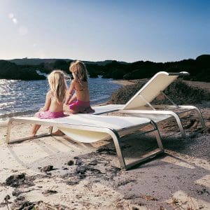 Image of kids sat on Coro L3 adjustable sun beds on sandy beach in the late afternoon sun