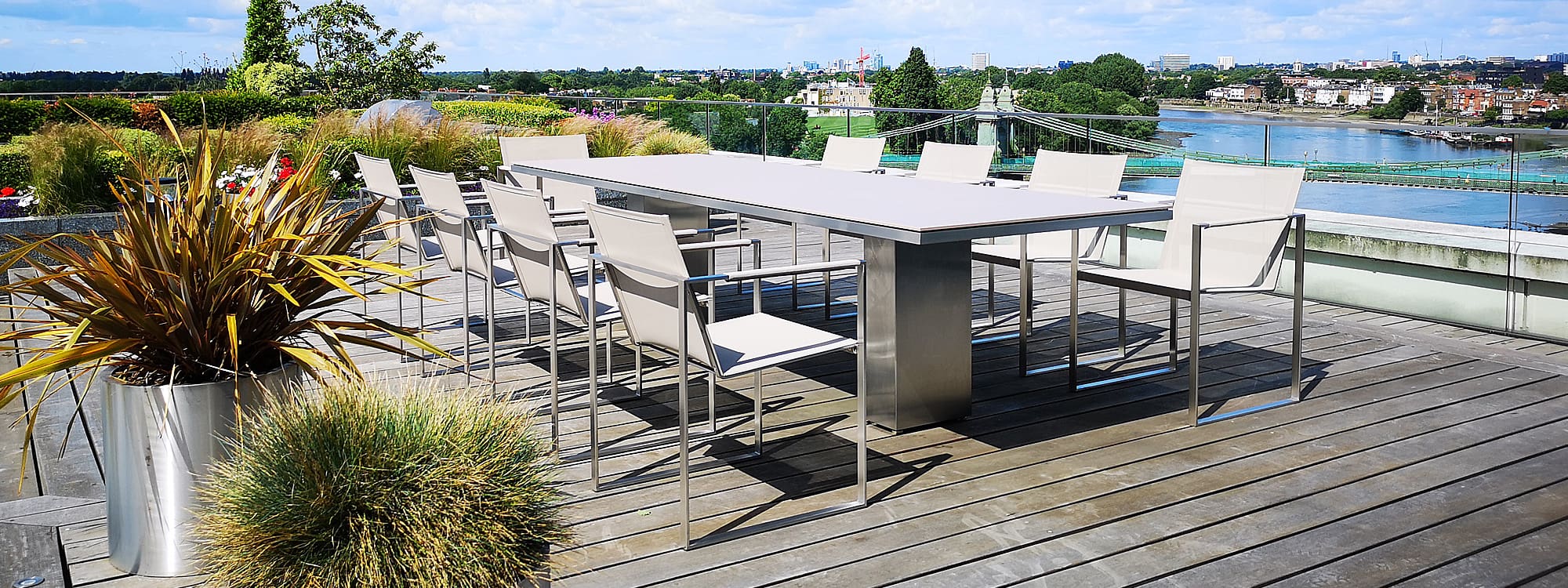 Image of FueraDentro Doble modern stainless steel garden table with taupe ceramic table top and Butaque dining chairs in London rooftop terrace