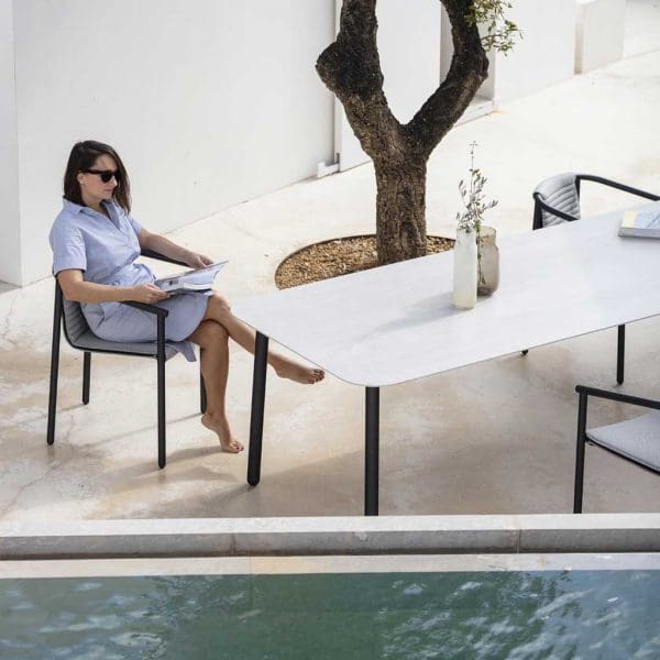 Image of birdseye view of woman sat in Duct Round garden chair next to Starling outdoor dining table