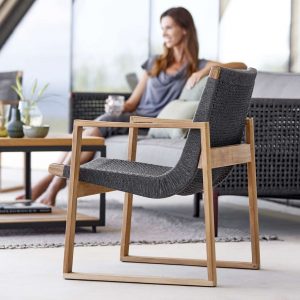 Image of Cane-line Encore lounge chair with woman sat on Encore sofa in the background