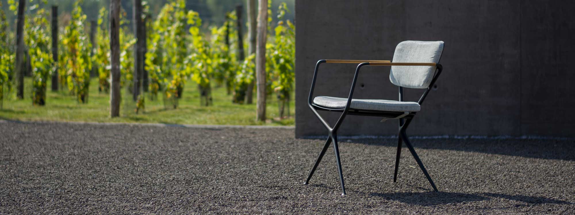 Image of black Exes chair with grey cushions sat on gravel by Royal Botania