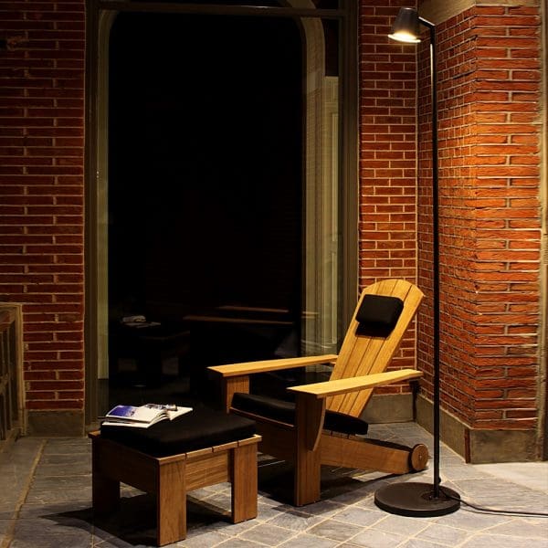 Nighttime image of New England luxury adirondack chair & footstool with black cushions by Royal Botania