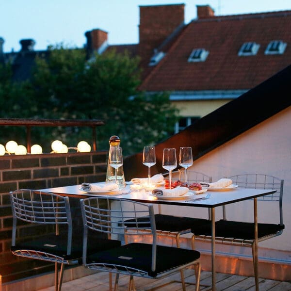 Image of Grythyttan Stålmöbler High Tech galvanised steel garden table and chairs on rooftop terrace at dusk