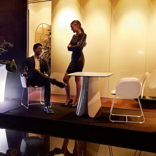 Nighttime image of Pezzettina table and chairs next to water feature with illuminated whitewashed wall in the background