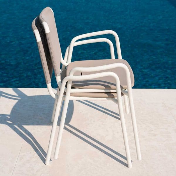 Image of 2 stacked Guest white garden chairs with taupe seat and back by RODA, shown on poolside