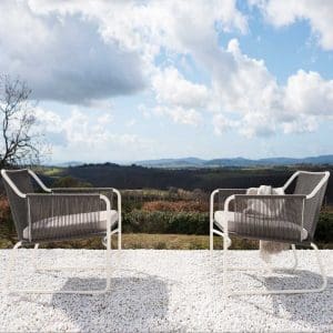 Image of pair of Harp modern garden lounge chairs on white gravel with Tuscan landscape behind