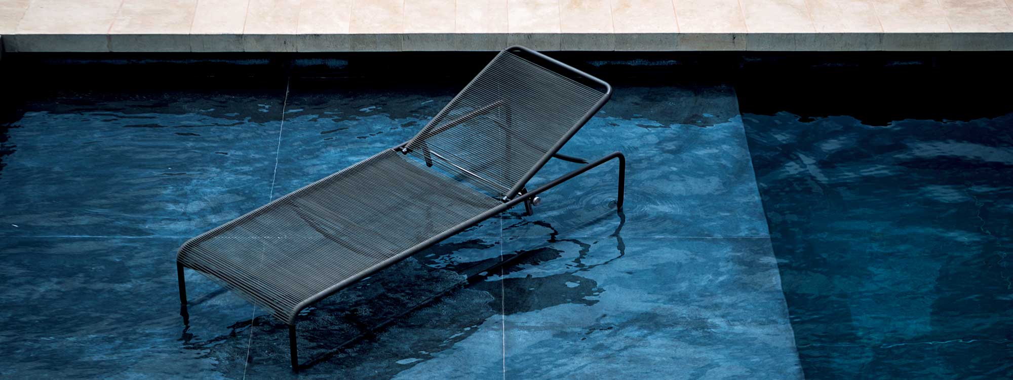 Image of RODA Harp black sun lounger sat in shallow water of a modern swimming pool