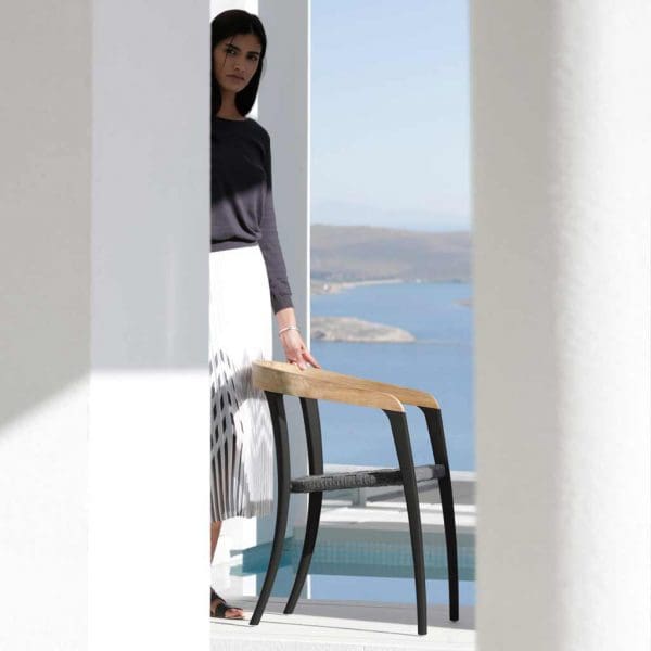 Image of woman stood next to black and teak Zidiz chair by Royal Botania