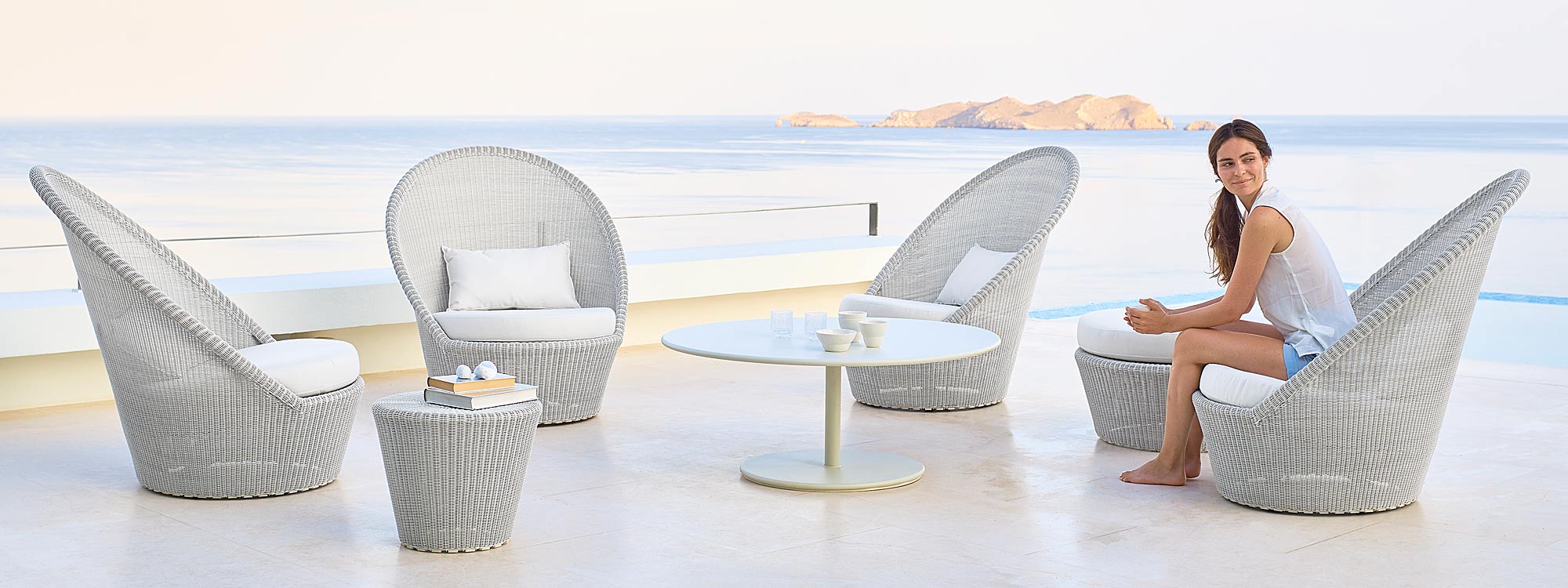 Image of white-grey Kingston high backed garden chairs by Caneline on terrace with sea and an island in the background