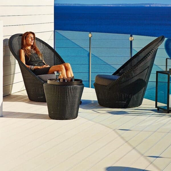 Image of woman enjoying the sun whilst sat in mocca-colored Kingston high backed garden chair by Caneline garden furniture