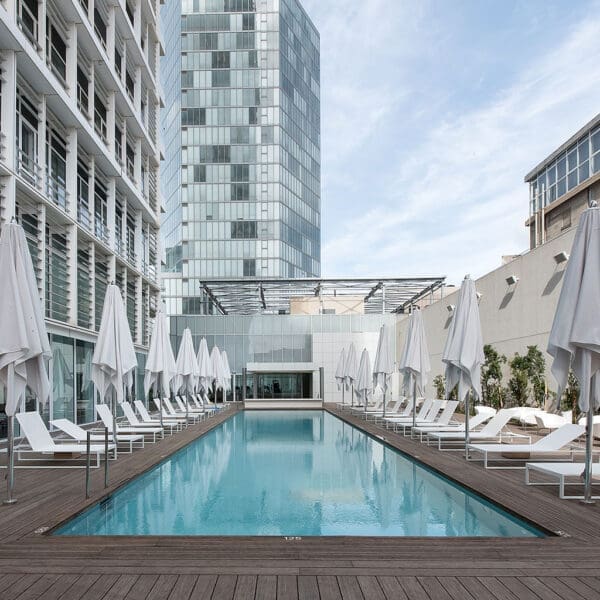 Image looking down the length of a hotel swimming pool, with Tuuci parasols and FueraDentro Siesta sun loungers on both sides