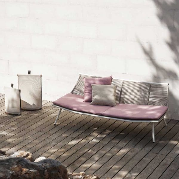 Image of RODA Laze modern Italian garden sofa in white with pink cushions, on decked terrace against white-washed wall