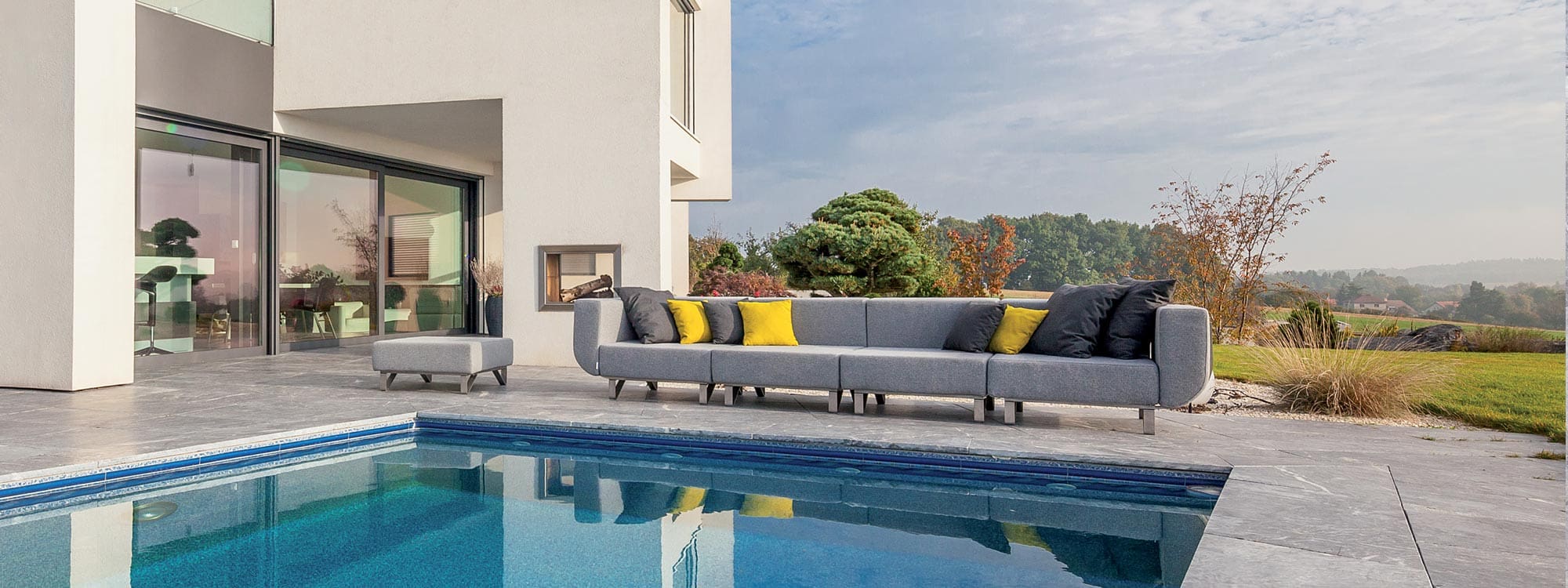Image of Lotos large outdoor sofa on poolside with reflection of the furniture shown in water