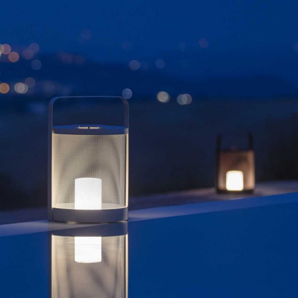 Image of Luci modern LED garden lanterns on poolside at light, with twinkling lights on far hillside in background