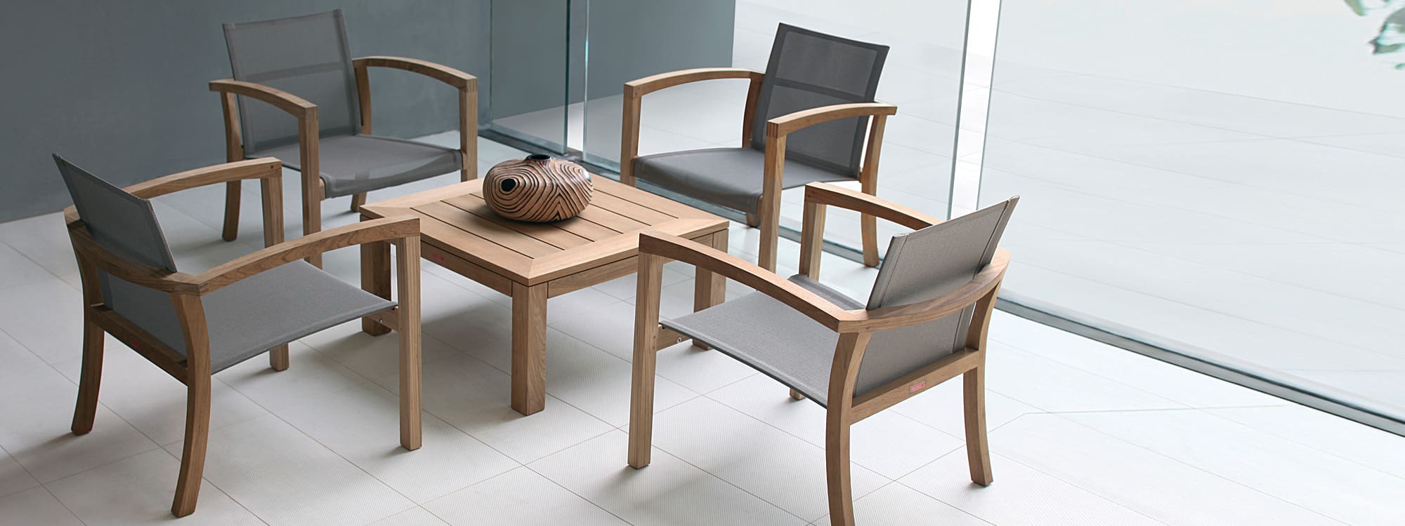 Image of four XQI lounge chairs sat around an XQI square low table by Royal Botania
