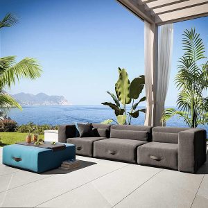 Image of Miami upholstered garden sofa in grey Sunbrella, with exotic plants, blue sea and sky in the background