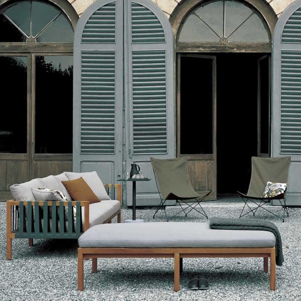 Image of RODA Mistral teak sofa with teal webbing and light grey cushions, next to Lawrence butterfly chairs on gravel terrace